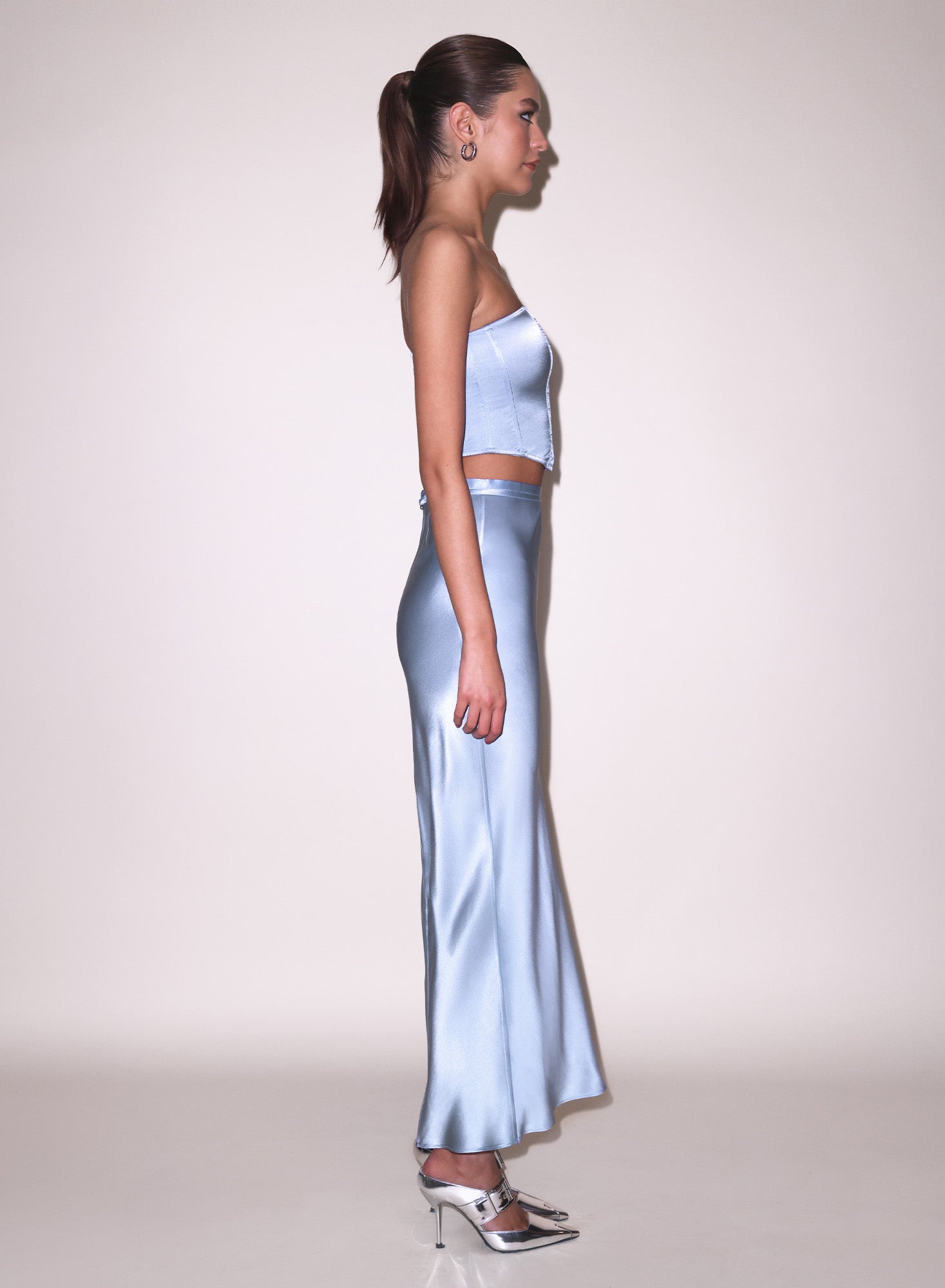 Model wearing a light blue satin strapless top and blue pencil skirt 